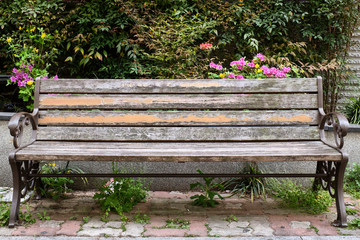 A shot of an old empty park bench with shrubbery in the background.