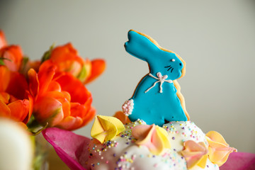 Easter bunny colourful cookie on top of the cake with flowers