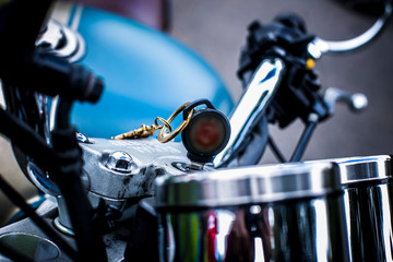 Plakat key in focus inside a static blue motorcycle, which is seen in an unfocused background and part of the handlebar