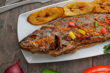 Grilled fish curry with plantain and salad. African national dish. Nigerian fish curry. Healthy...