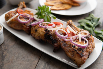 Grilled chicken with red onions. African food meal. Nigerian national dish. Fresh and healthy with tomatoes and red onions. Fried food. Fresh salad with peppers Cuisine