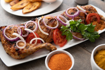 Grilled chicken with red onions. African food meal. Nigerian national dish. Fresh and healthy with tomatoes and red onions. Fried food. Fresh salad with peppers Cuisine