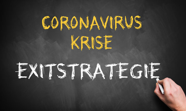 hand writing the German message for CORONAVIRUS CRISIS - EXIT STRATEGY on a blackboard