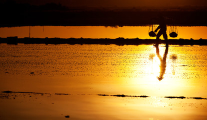 Salt and Silhoutte of salt farmer on salt field Hon Khoi, Nha Trang, Khanh Hoa, Vietnam.