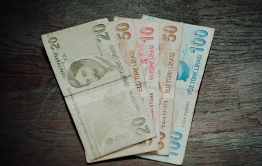 Many hundred Turkish lira on wooden table background texture. bundles of money scattered on the...