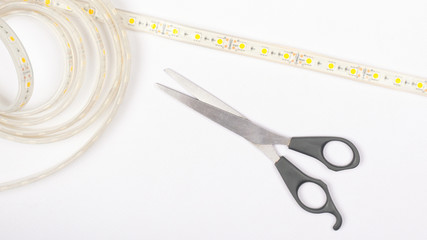 LED tape and scissors on a white background top view.