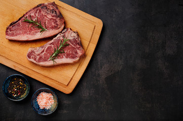 Raw Dry Aged Beef Steak. Raw Dry Aged Meat. Raw sirloin steak on a wooden board with four peppers...