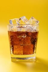 cup of iced cola on a yellow background