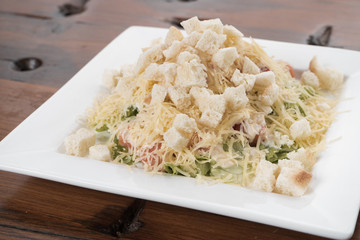 Delicious salad with croutons, grilled chicken breast, grated parmesan cheese and cos lettuce, with sauce in the gravy boat, simply and healthy recipe