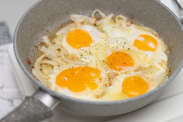Fried eggs with onions in a frying pan. The concept of a healthy Breakfast and proper nutrition.