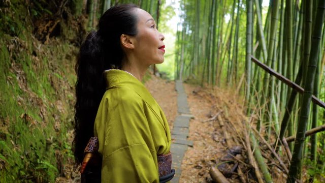 Elegant Japanese woman walking through a bamboo forest in Kyoto Japan