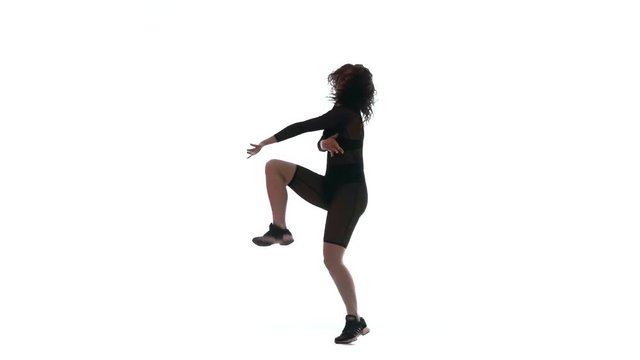 silhouette of a young beautiful girl in a black transparent tight suit energetically dancing dancehall, street dance, twerk against white background, isolated