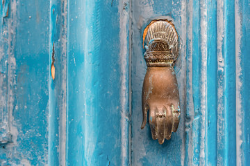 Background from an old blue wooden door with a bronze handle in the shape of a hand.