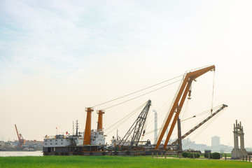 The sand pumping vessel and the  semi-submersible heavy lift vessel berthed along the river.