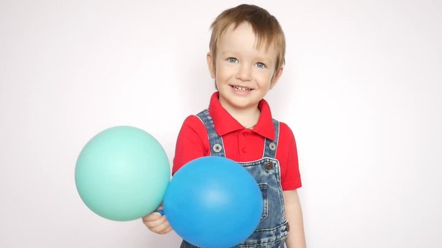 A cheerful little boy shows the azure and blue balls in his hand