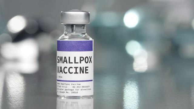 SmallPox vaccine vial in medical lab with syringe placed next to it.