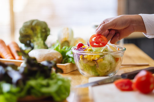 Closeup image of a female chef cooking a fresh mixed vegetables salad in kitchen