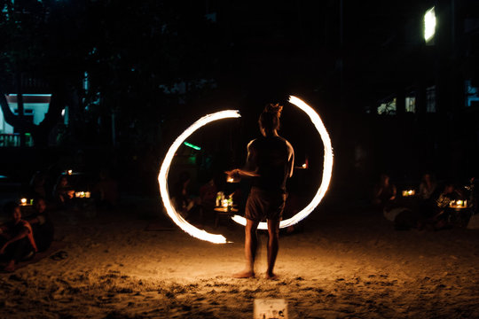 Rear View Of Man Spinning Fire On Field At Night