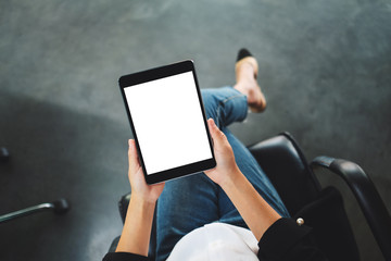 Top view mockup image of a woman sitting and holding black tablet pc with blank white desktop screen