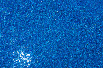Swimming pool, blue clear water in the outdoor pool, with sun flare on the surface. Background of blue water in the pool