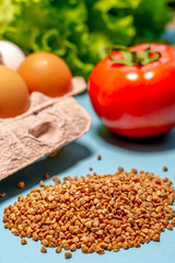 Heap of buckwheat, tomatoes, eggs and salad close-up on a blue background