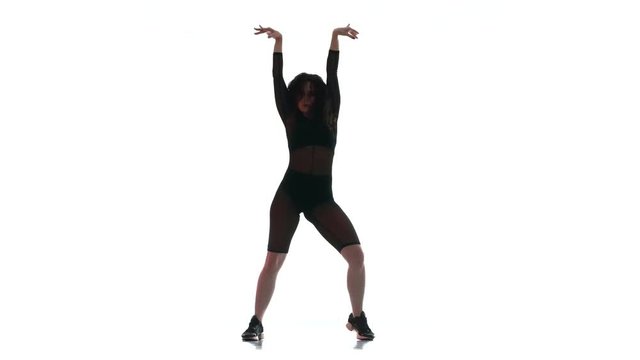 young beautiful woman in a black transparent tight suit energetically dancing dancehall, street dance, twerk against white background,  isolated 