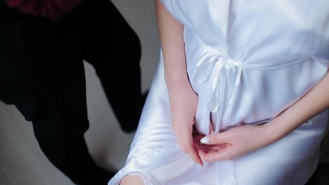 Women's hands on her knees. A girl in a white coat is painted by a makeup artist.