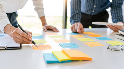 young business workers posting with sticky notes stickers reminders  creative brainstorming at...