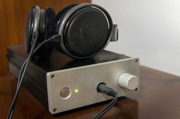 Obraz na płótnie Canvas A pair of hifi headphones and a professional amplifier on the wooden table. It is a common set of audio equipment for music lovers. 