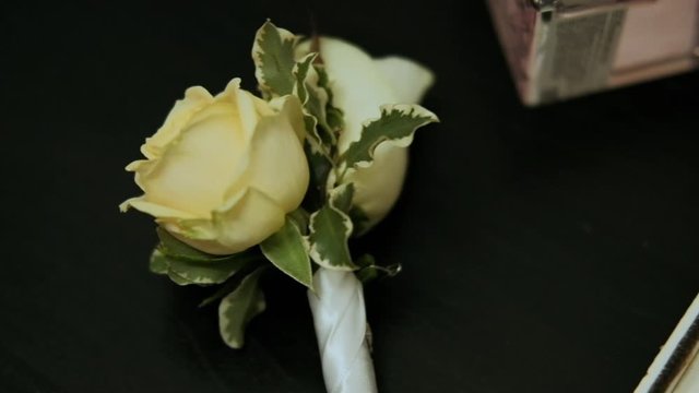 a man in a jacket hangs a white buttonhole of a rose