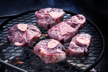 Beef shanks on a barbecue grill over coals