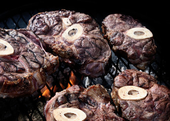 Beef shanks on a barbecue grill over coals