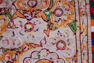 Fototapeta na wymiar hand embroidered cross on the canvas. Wooden table and thread stranded cotton on the background, india embroidery handicrafts close-up view