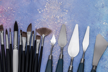 Artistic palette knives and drawing brushes, creative tools of various sizes and shapes on a worn...