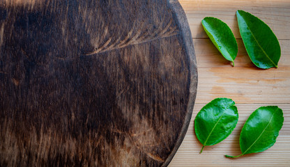 green lemon leaf on wood cutting board.