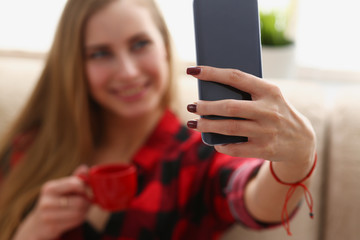 young blond pretty woman drinking coffe and look at laptop in morning sit on sofa