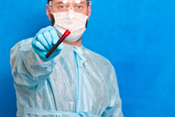 Male scientist holding test tube with blood on blue background