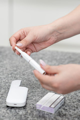 Electronic Cigarette Technology. Tobacco IQOS system. Close-up of a girl smoking an electric hybrid cigarette with a heating pad. tobacco heating system. Electronic cigarette in female hands.