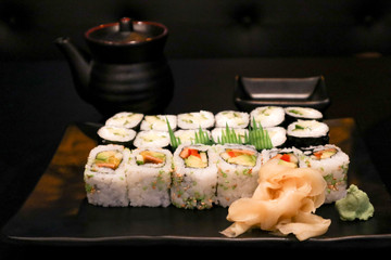tasty Japanese sushi on a black plate with saucer on the black table
