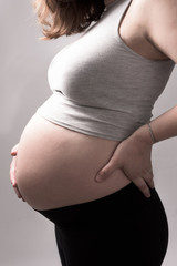 woman touching her pregnant belly. Close up tummy. Expecting a baby. Young and happy pregnant. Healthy pregnancy. close up belly. Muscled gray.