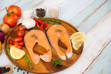 Fresh raw salmon steak with colorful vegetable and hot spice ingredient on wood plate in color wood plank background