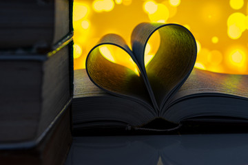 Expanded book in the shape of a heart, yellow bokeh