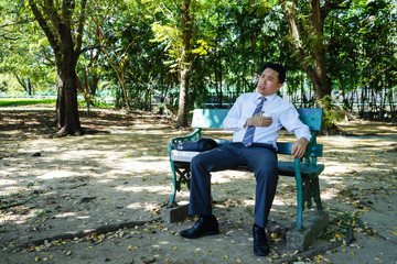 Middle aged businessman is suffering from heart attack at a park in Bangkok.