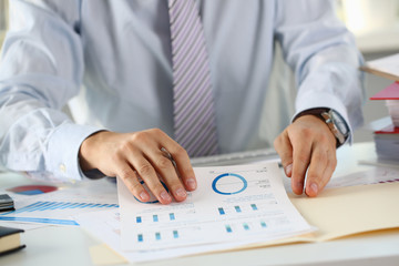 Fototapeta premium Male hands hold documents with financial statistics at office workspace closeup. White collar check money papers stock exchange market internal Revenue Service inspector earning list concept
