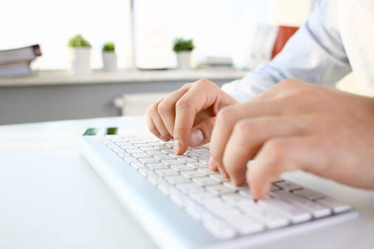 Male arms in suit typing on white keyboard using computer pc at office workplace closeup. Accountant finger job modern lifestyle web search assistant enter account login password and note credential
