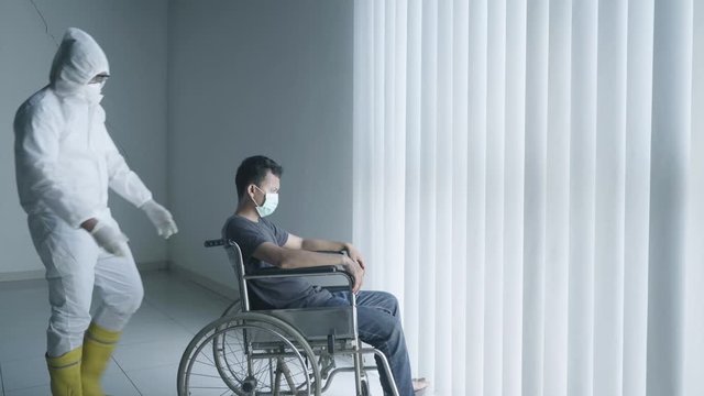 Disabled man with doctor after sunbath near window