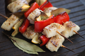 Close-up of baked fish souvlaki with cod fillet, red bell pepper, bay leaves and lemon, studio shot