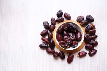 Dried dates fruit in ceramic bowl on wooden table. Top view.