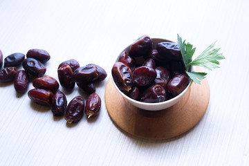 Dried dates fruit in ceramic bowl on wooden table. Top view.