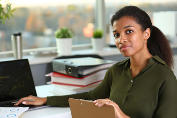 Beautiful black smiling businesswoman portrait at workplace look in camera. White collar worker at...